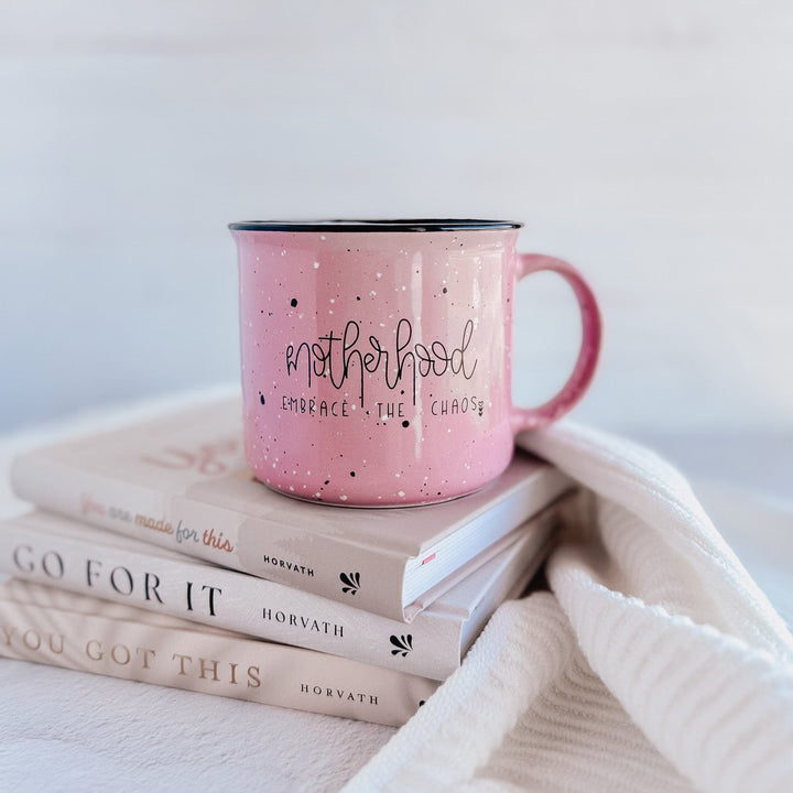 Pink mug with text on a stack of books with motivational quotes